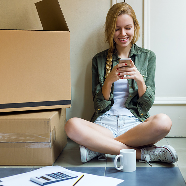Portrait of young woman with mobile phone in her new house.