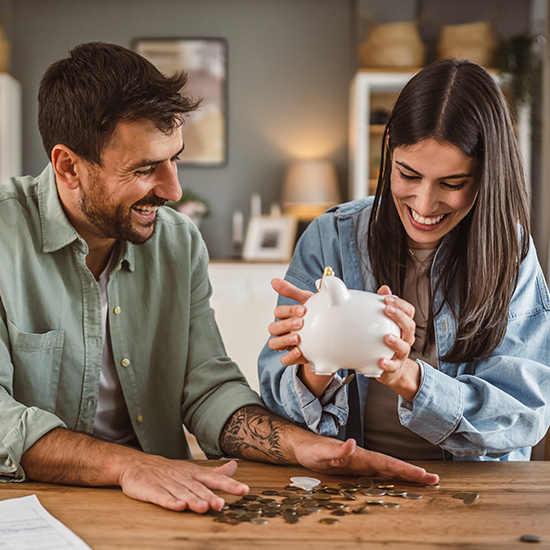 Happy boyfriend and girlfriend save money together in the piggy bank